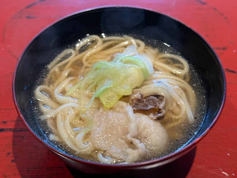 黒の椀に取り分けた熊うどん。熊肉と葱が載る