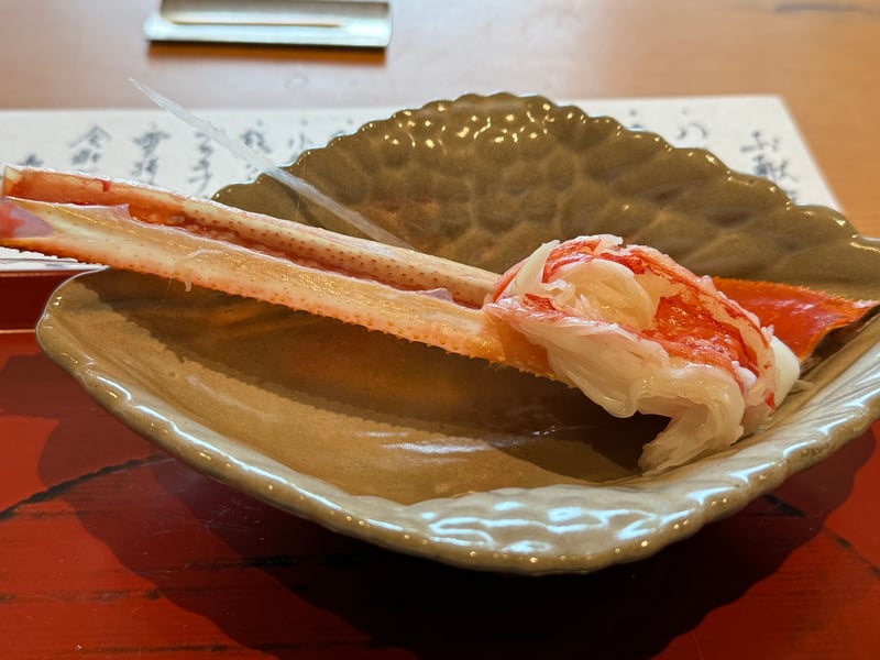 緑釉の葉形の皿に、殻を開いたズワイガニの脚一本