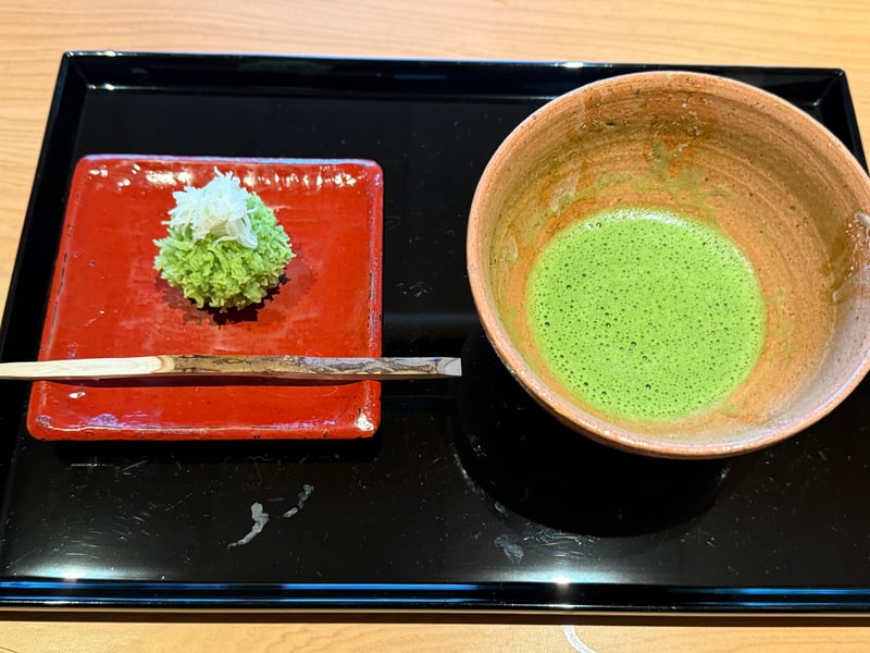 黒の盆に、緑のきんとんに白い百合根を載せた雪持柑と、抹茶茶碗