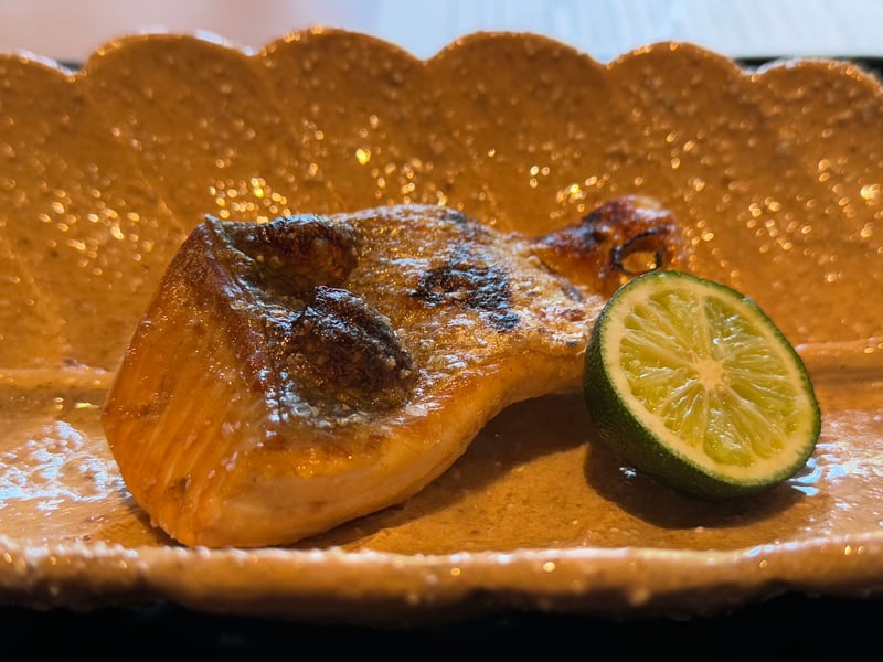 飴釉の輪花皿に桜鱒の炭火焼き。皮に焼き目が入り、半割りのすだちが添う