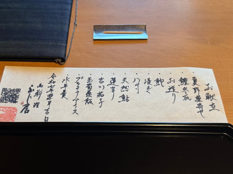 黒い盆に載せた手書きの葉月の献立。夏野菜寄せから水羊羹まで12品