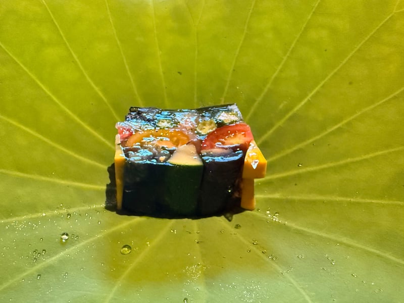 蓮の葉に載せた白海老と夏野菜のゼリー寄せ。断面にトマトとオクラが見える
