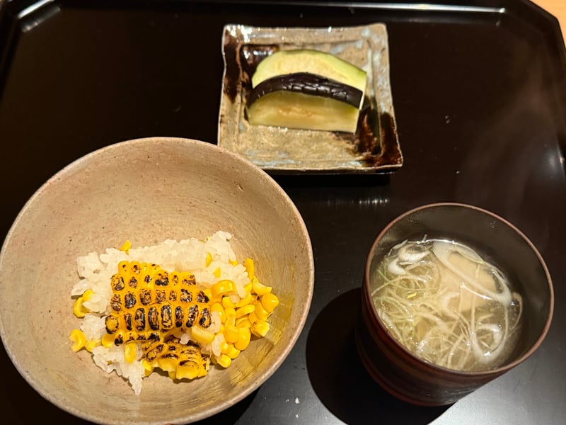 取り分けたとうもろこしご飯に、茄子の漬物と汁物