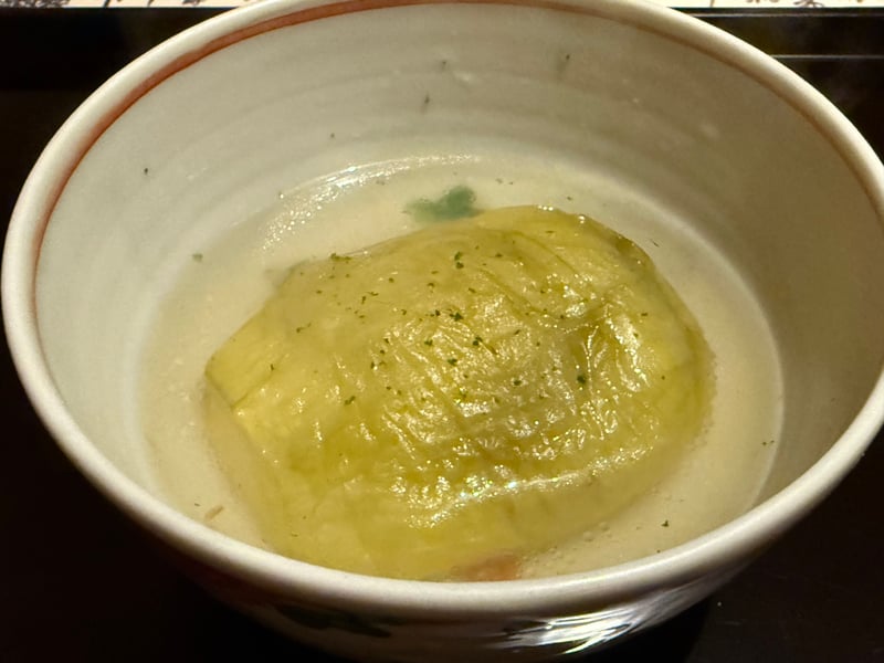 白い鉢に、皮をむいた吉川なしを丸ごと澄んだ出汁に浸して、すり柚子を散らしてある