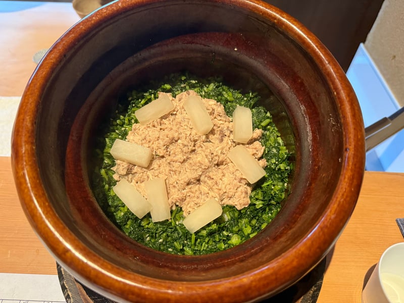 土鍋の中。刻んだ大根葉の上にほぐしたぶりと大根
