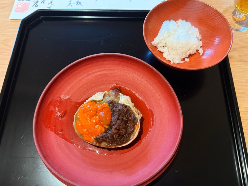 朱の皿にのった甲箱の甲羅。内子と蟹味噌を盛り、朱の椀に銀シャリが添う