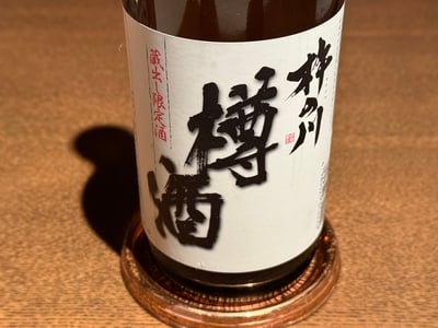 銅の小皿に載った、神の川 樽酒 蔵出し限定酒の瓶