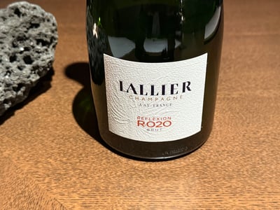 木のカウンターに置かれた Lallier のシャンパーニュ、Réflexion R.020 Brut の瓶