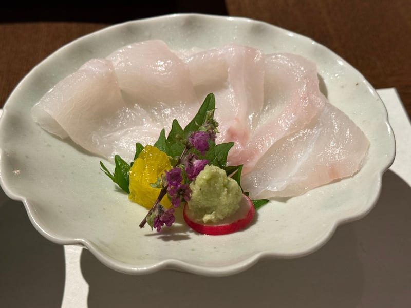 白い輪花の皿に、厚く引いた九絵が5切れ。穂紫蘇とわさび