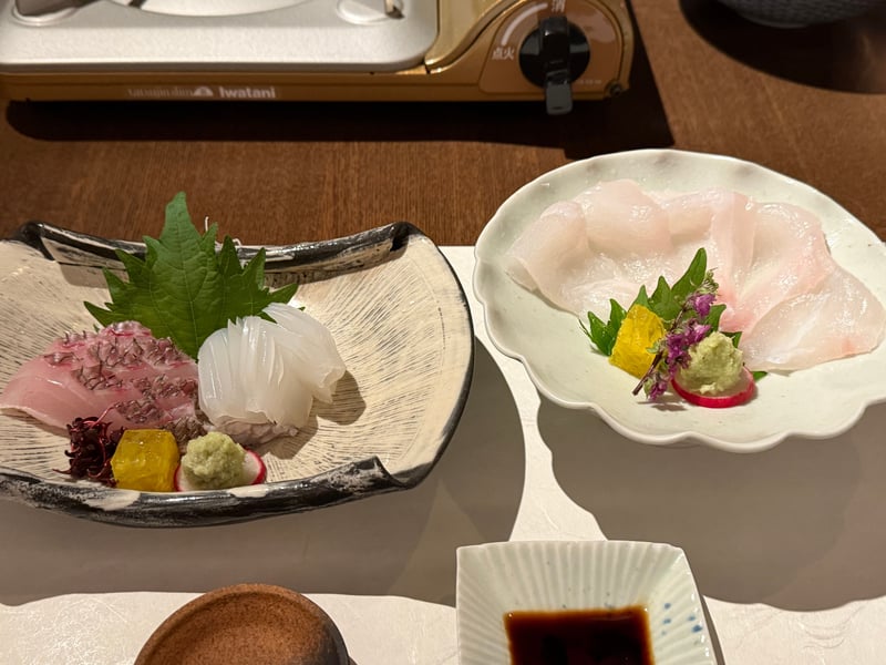 造里の二皿。左に真鯛の松皮造りと水烏賊、右に厚く引いた九絵。奥に卓上コンロ