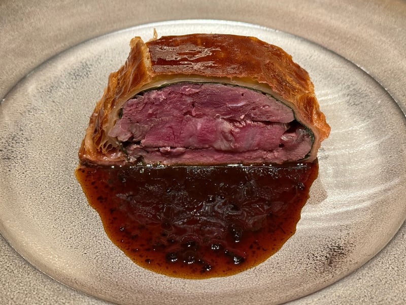 パイで包んで切った野生肉包の断面と、深い色のソース