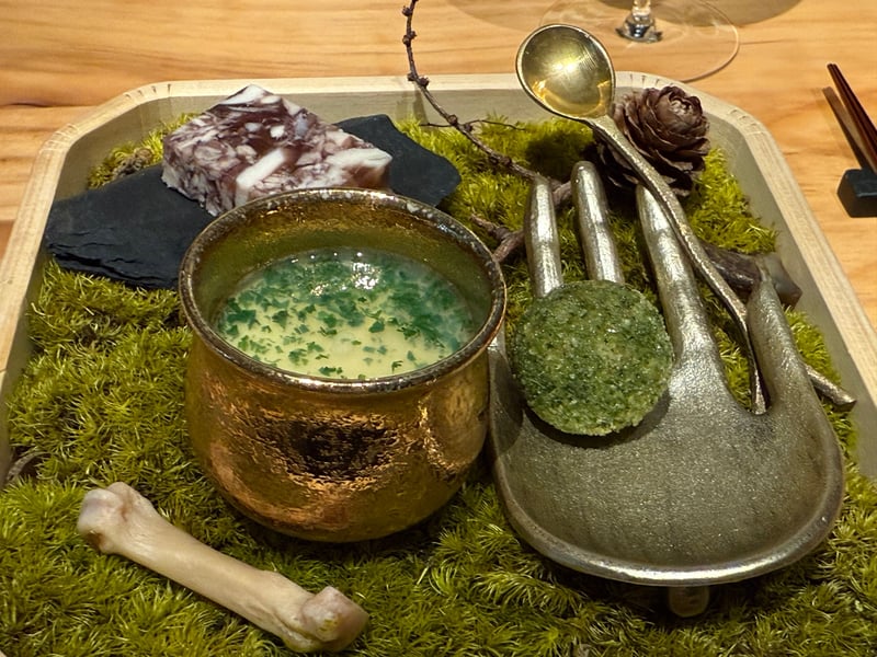 苔を敷いた木の盆に、鹿肉のコロッケ、蛤の茶碗蒸しを入れた金色の小鍋、信玄鶏と猪のプレッセ