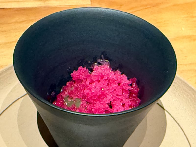 黒い器に盛った桃色の梅のグラニテ。山椒の実が混ざっている