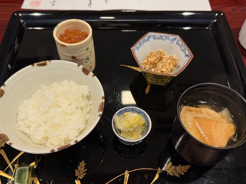 黒い盆に、白飯、はらこの醤油漬けの猪口、衣をつけて揚げた猪、白菜の漬物、油揚げの味噌汁