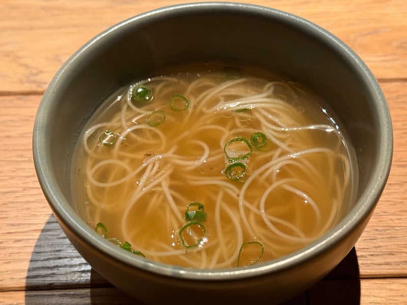 灰緑の椀に、澄んだあごだしの五島そうめん。青ねぎの小口切りを散らす