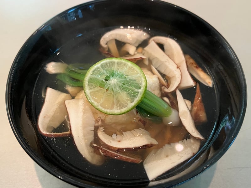 黒い椀に張られた澄んだ出汁。薄切りの松茸が重なり、すだちの輪切りと青菜が添えられている