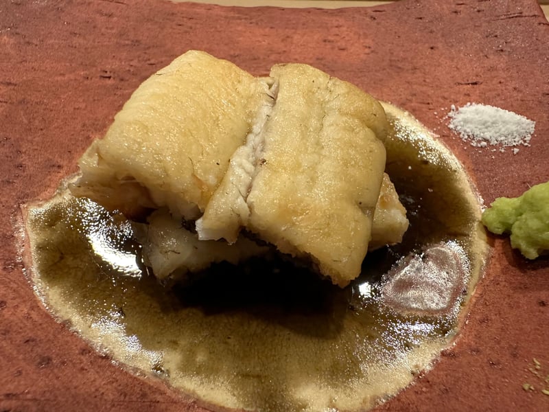 赤茶の皿に焼いた天然鰻。タレが溜まり、塩とわさびが別添えになっている