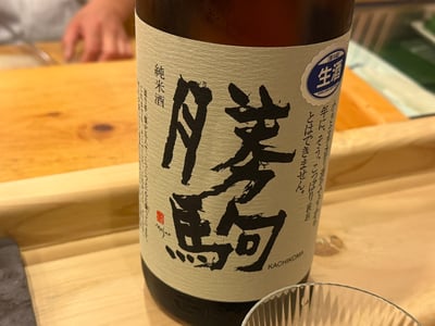 カウンターに置かれた勝駒 純米酒 生酒の一升瓶とグラス