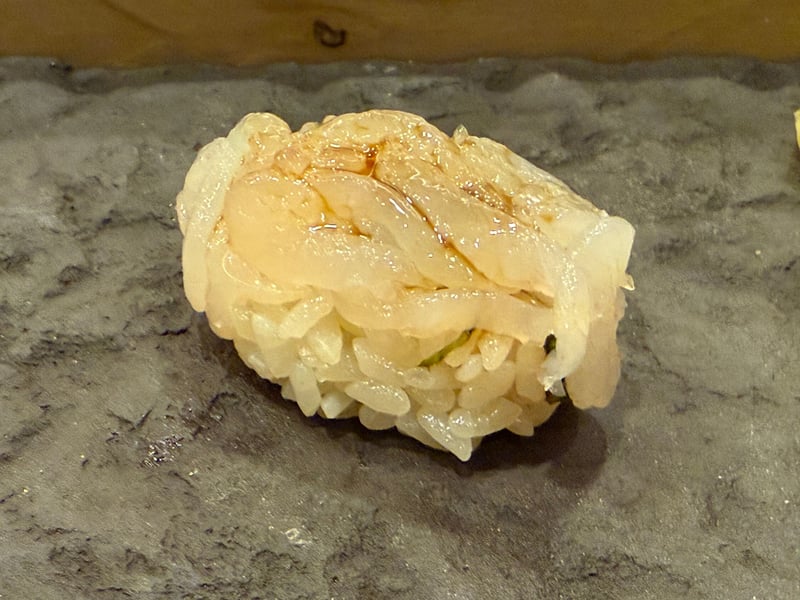 白海老の小さな身を重ねた握り、シャリとの間に海苔が一枚