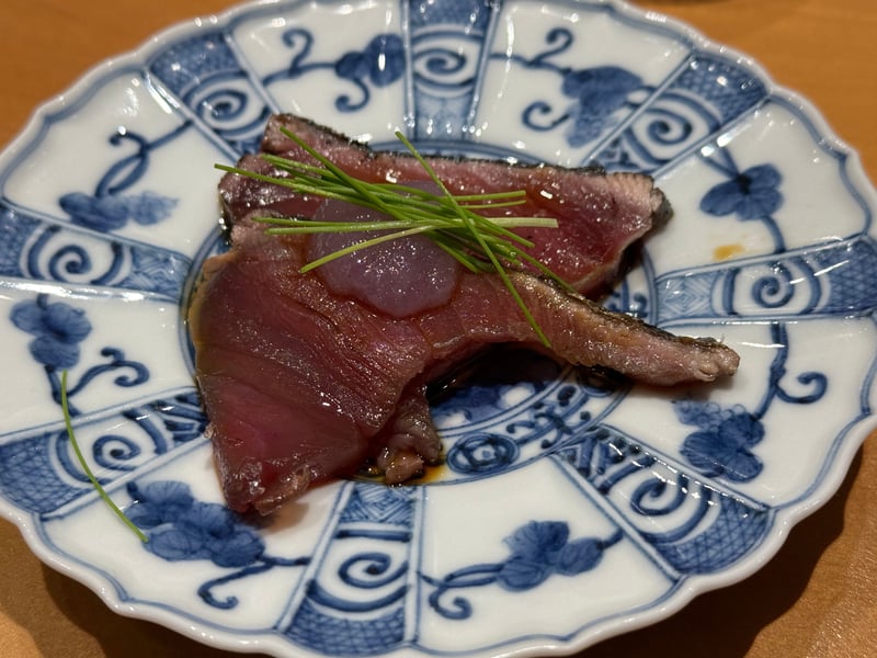 染付の皿に、皮を焦がした鰹の藁焼きを二切れ、芽ねぎをのせて