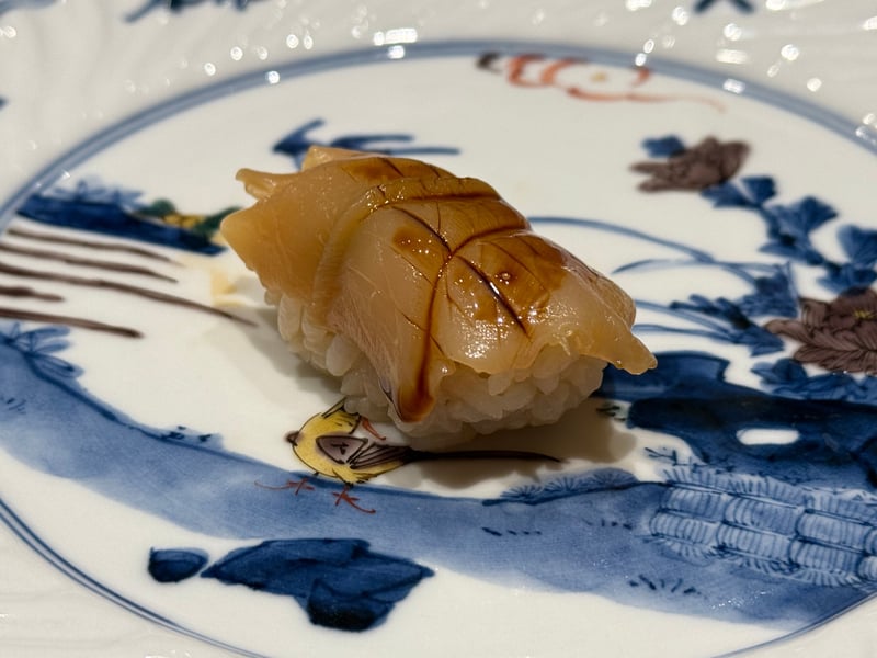 厚みのある白い身を開き、煮ツメを一筋引いた万寿貝の握り