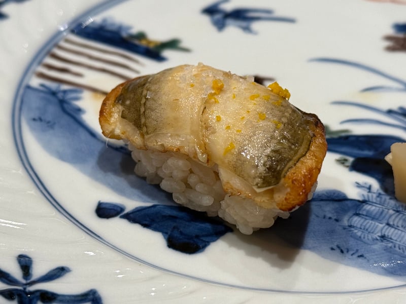 染付の皿に、焼いた穴子の握り。塩と柚子の皮を散らして