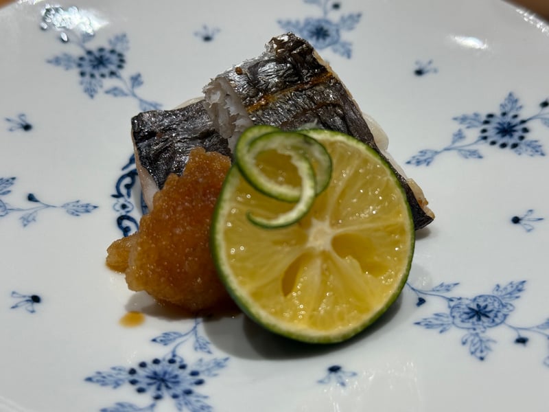 染付の皿に、皮を焼いた太刀魚の握り。大根おろしと輪切りの酢橘を添えて