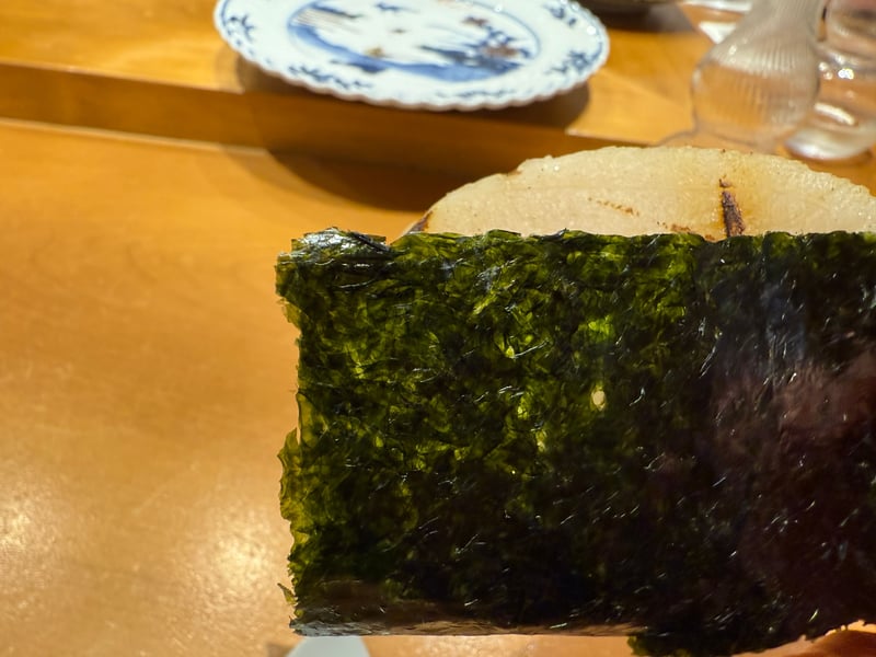 手渡された海苔巻き。奥に焼き目の付いた大きな平貝の貝柱が見える