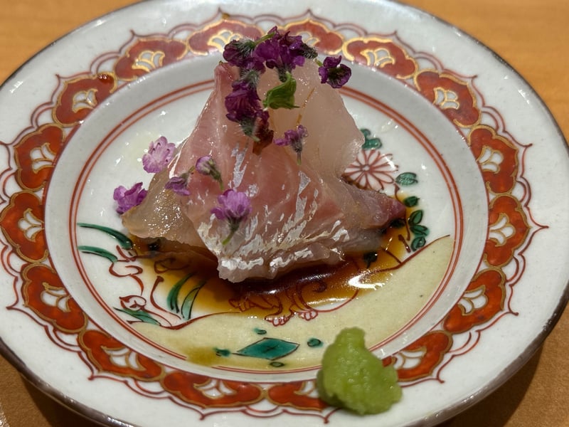 九谷の皿に鯛の刺身を重ね、紫の花穂紫蘇とわさびを添えて