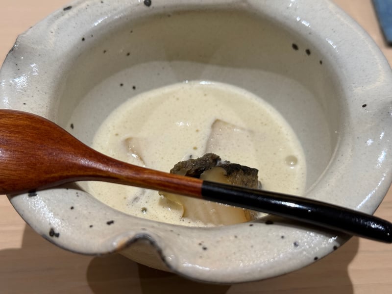 白い鉢の泡立った肝ソースに沈む蒸し鮑、木の匙が添えてある