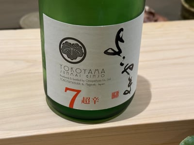 カウンターに置かれた「よこやま」の緑瓶。ラベルに YOKOYAMA JUNMAI GINJO と 7 超辛