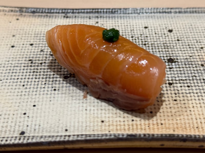 橙色のサクラマスの握り、上に緑の薬味が一点