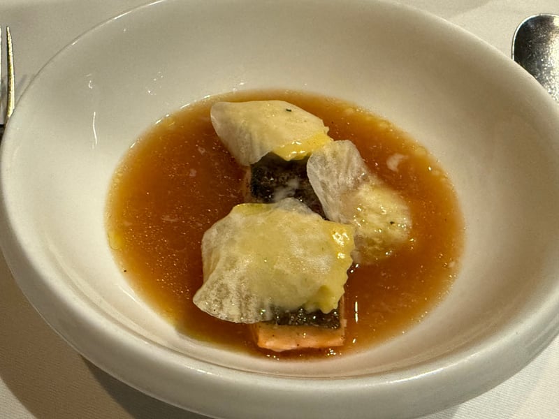 琥珀色の澄んだ出汁に、皮を焼いたホッキョクイワナ。上にアニョロッティが3つ
