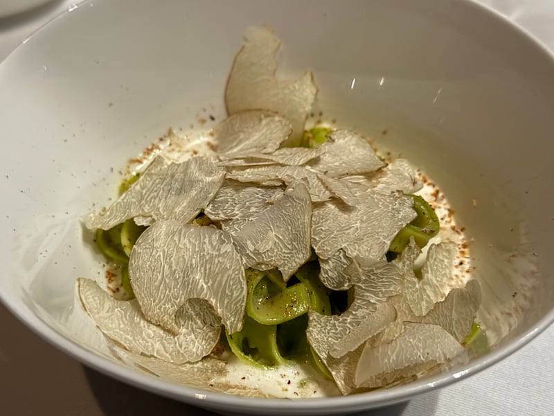 緑のパスタに白トリュフを薄く削って一面に重ねる。白いソースとパン粉