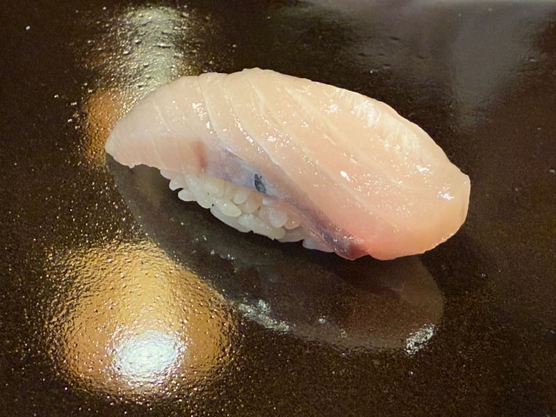 黒いつけ台に、塩で締めたさわらの背中の握り