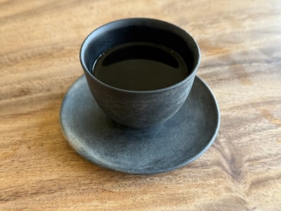 黒い碗と受け皿に注がれた、褐色のくび木茶