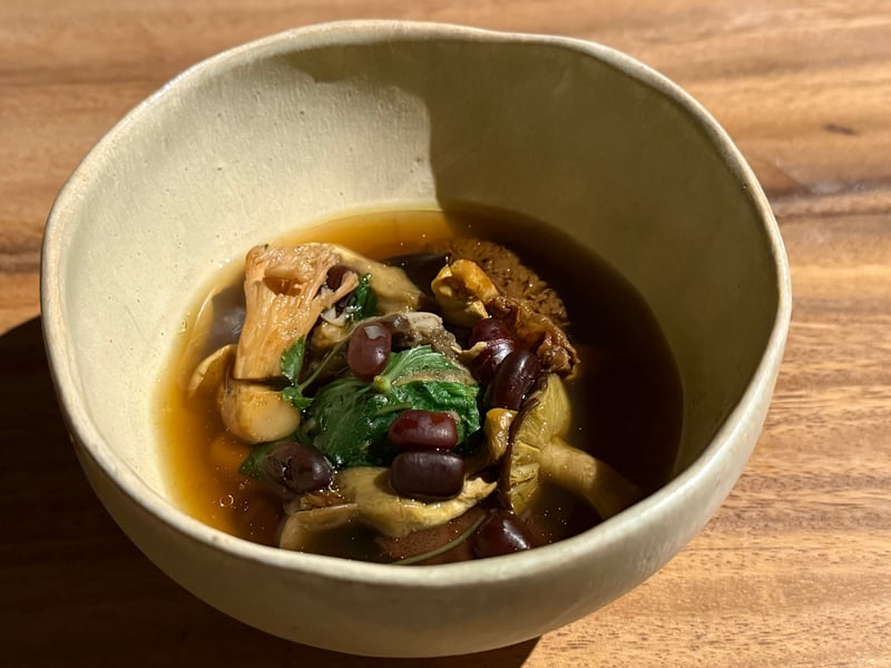 白い碗に張ったいとこ汁。小豆と天然きのこ、青菜が浮かぶ