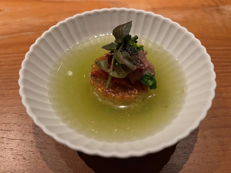 白い鉢に淡い緑の出汁。香ばしく焼いた生姜玄米の塊が沈み、梅と青菜、大葉がのる