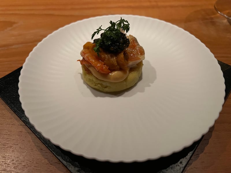 白い皿の中央に小さな芋のパンケーキ。海老と雲丹をのせ、キャビアとチャービルを頂に置いてある