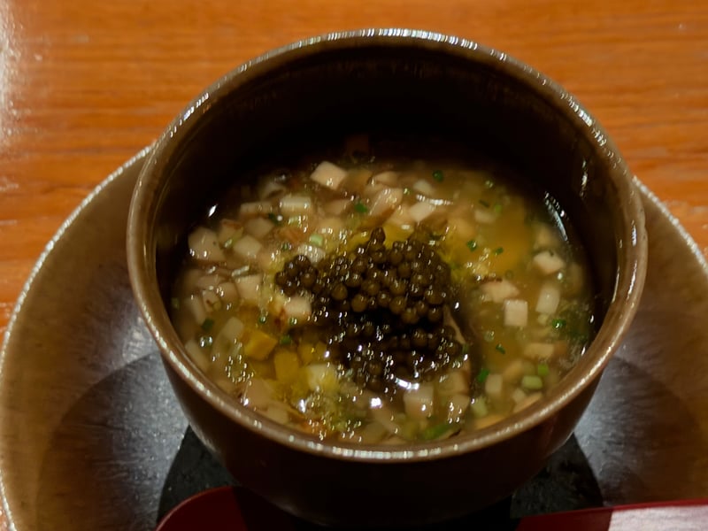 茶色の椀に刻んだ車海老と松茸、九条葱と柚子を浮かべ、中央にキャビアを盛った汁もの