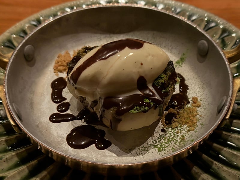 銅の器に抹茶をまとった土台とアイスクリームを重ね、チョコレートのソースを散らしたデザート