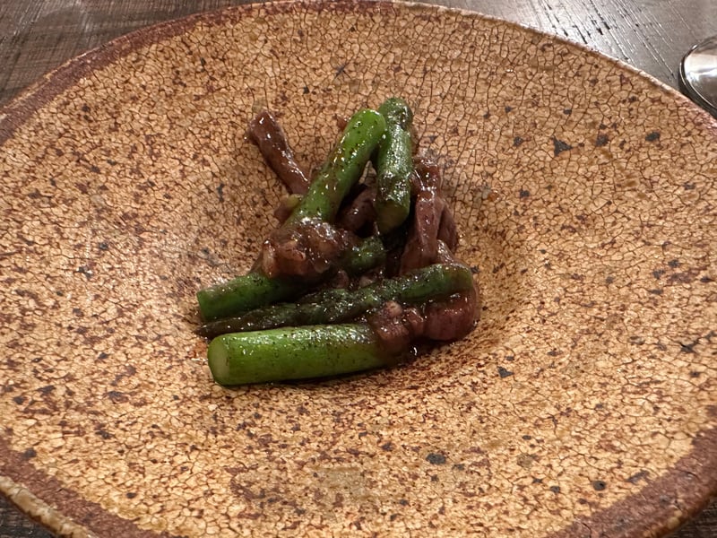 茶色い皿に盛られた魚とアスパラガス
