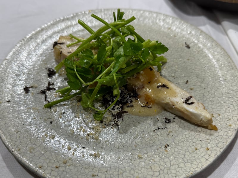 貫入の入った白い皿に、地鶏の胸肉と緑の葉。白く削ったものと黒トリュフを散らしてある