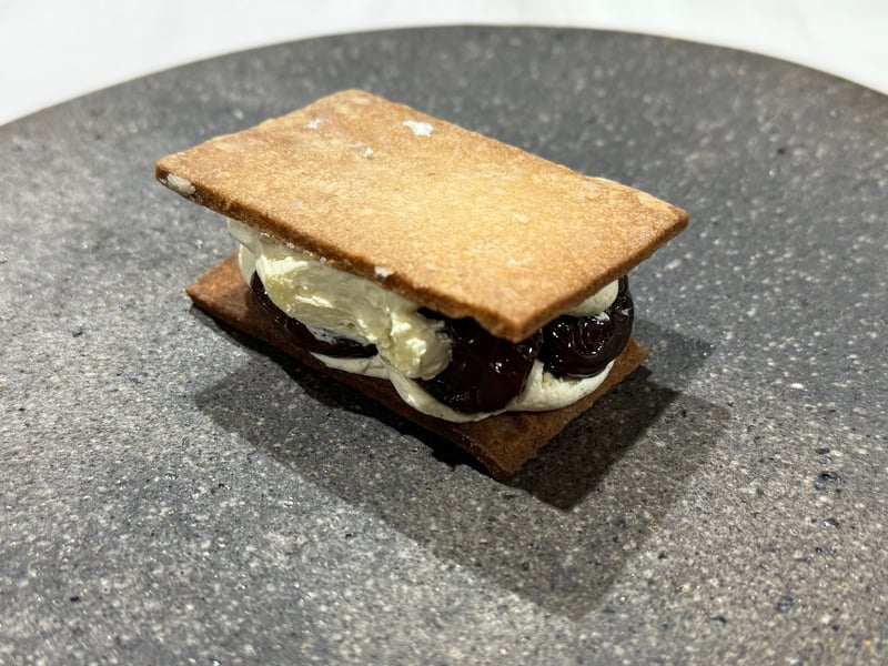 薄い焼き菓子二枚に、白いチーズと黒いレーズンを挟んだサンド