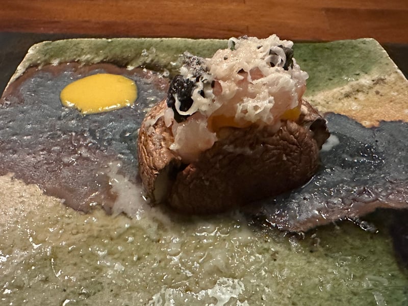 緑釉の皿。焼いたきのこにおろしと黒い薬味、黄色いソース