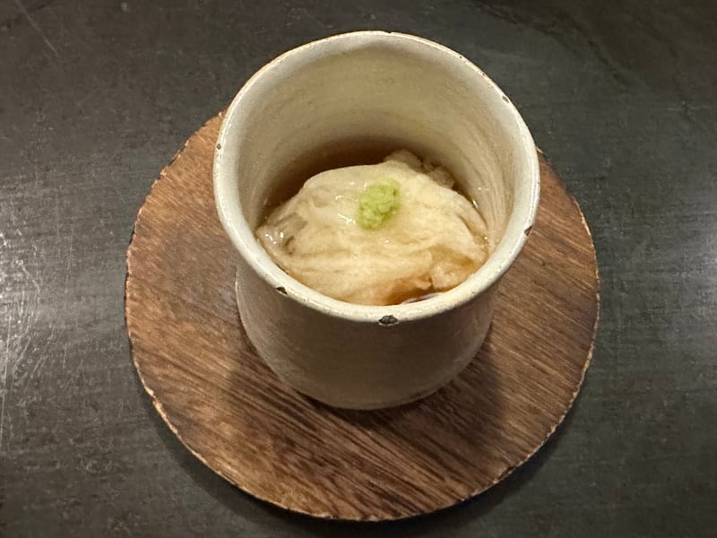 白い小さな器。出汁の中に白い蒸し物とわさび