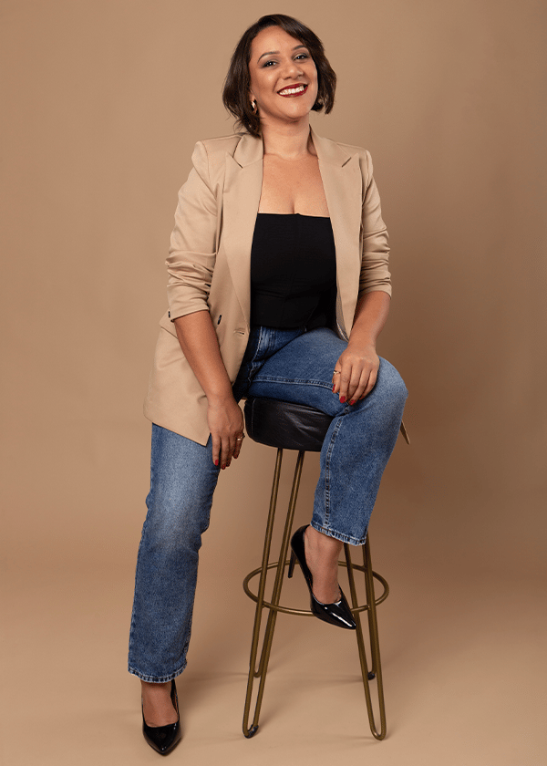Mulher de blazer bege fotografada sobre fundo infinito bege