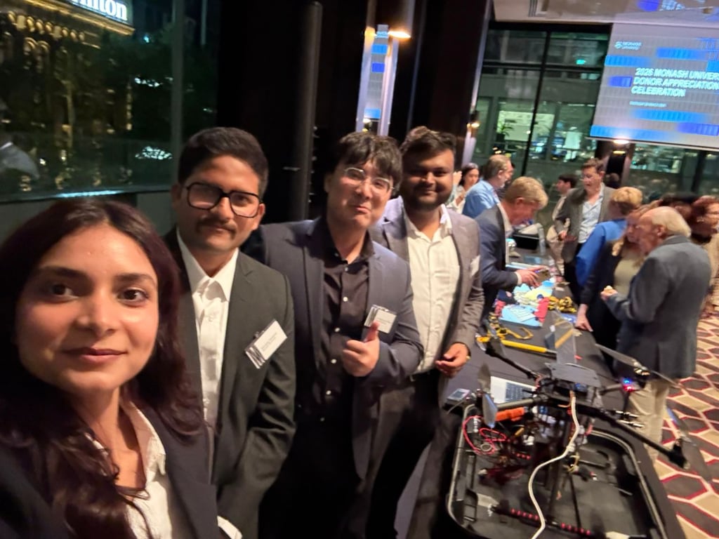 Four teammates in formal wear at Monash donor celebration with drone display