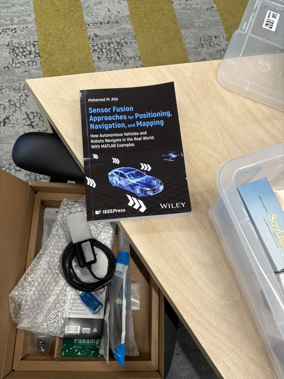 Sensor fusion textbook and boxed electronics on a wooden desk