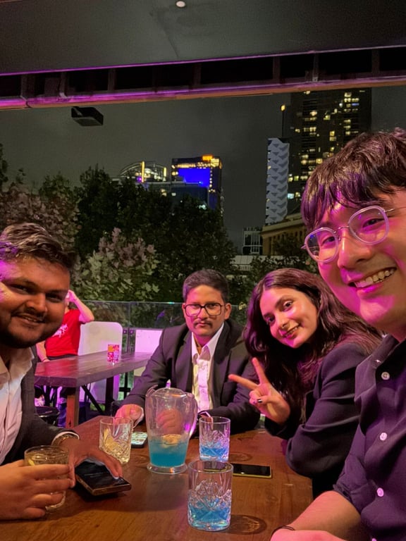 Four teammates at a rooftop table at night with city lights behind